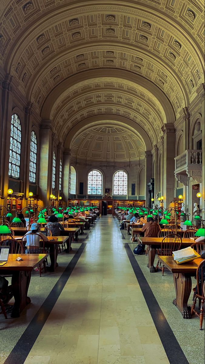 the inside of a large building with tables and lamps on each side of the room