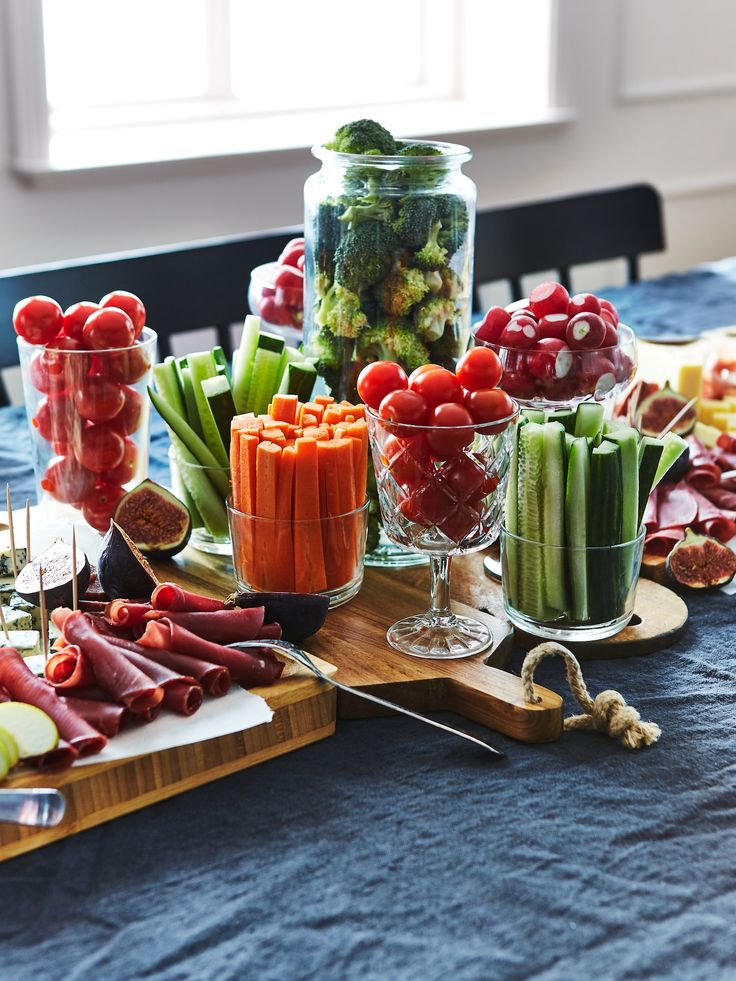 a table topped with lots of food and veggies on top of a wooden cutting board