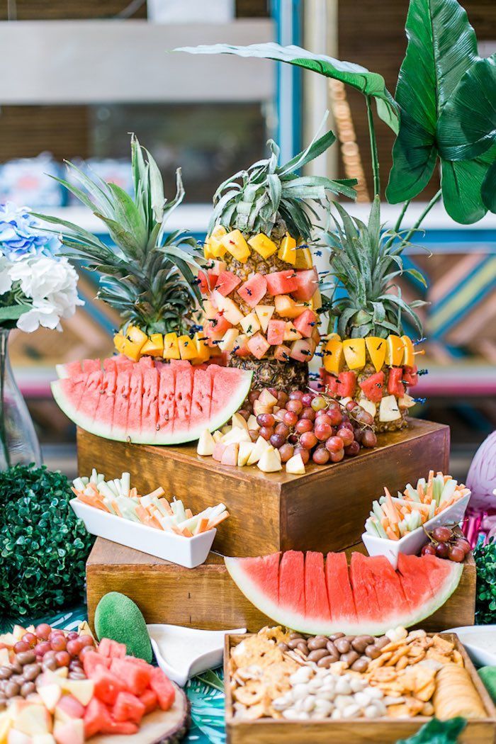 a table topped with lots of watermelon and pineapples next to other foods