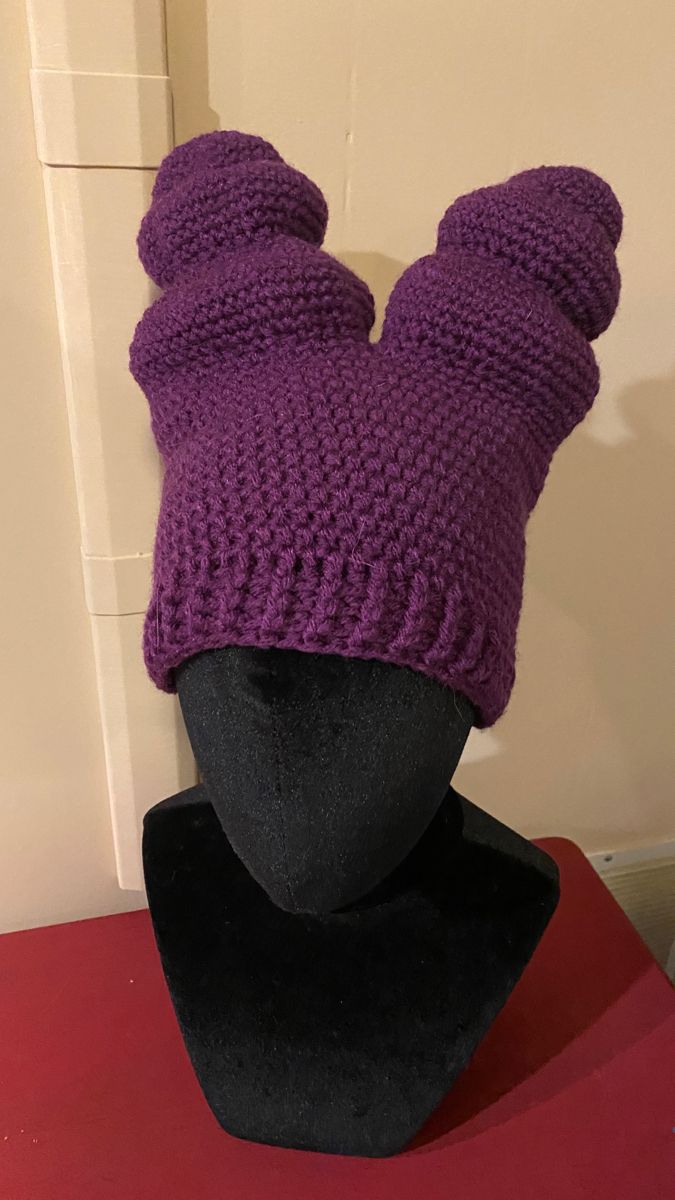 a purple knitted hat sitting on top of a mannequin's head