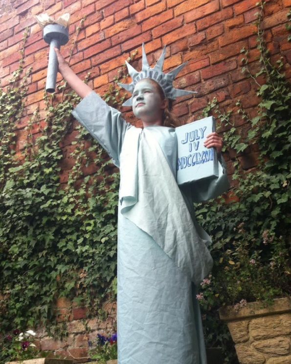 a statue of liberty holding a sign in front of a brick wall