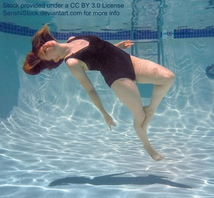 a woman in a black swimsuit is diving under the water with her legs spread out