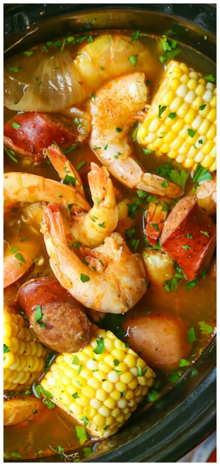 a crock pot filled with shrimp, corn and potatoes