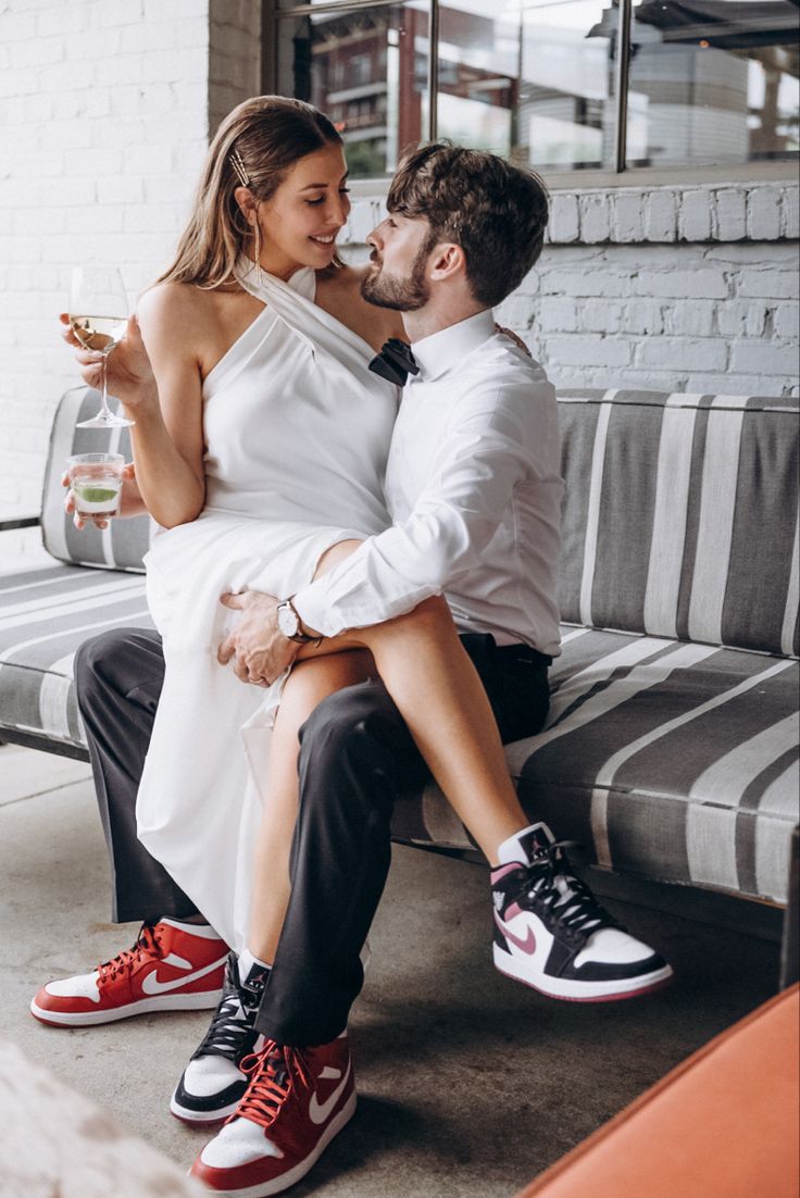 a man and woman are sitting on a bench drinking wine while they both look at each other