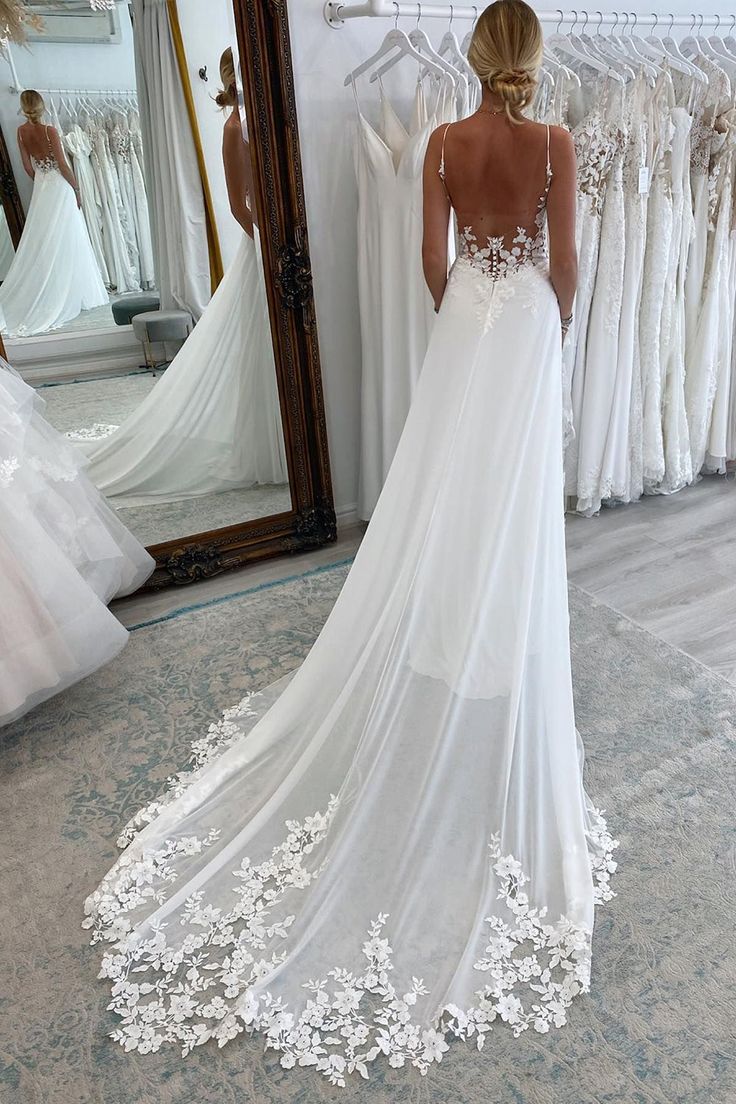 a woman standing in front of a mirror wearing a wedding dress