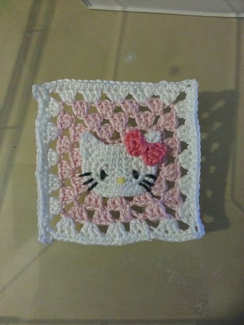 there is a crocheted square with a hello kitty on it and a rose in the center