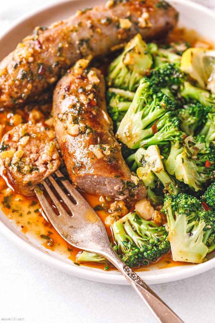 a white plate topped with meat and broccoli covered in sauce next to a fork