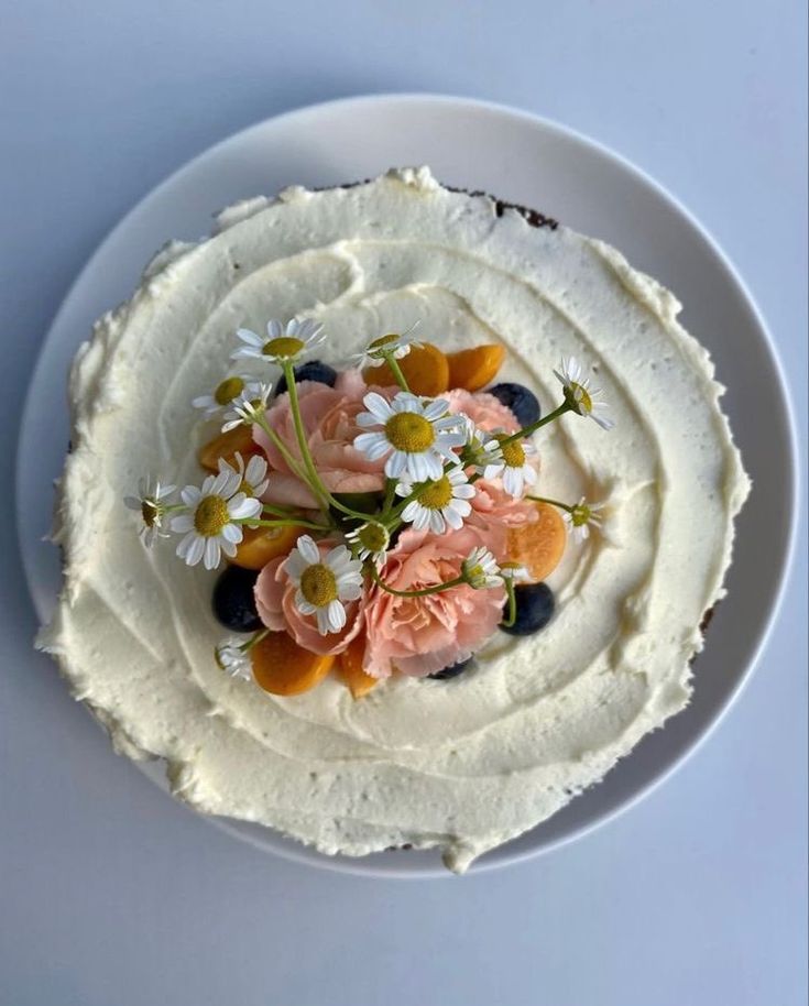 a white plate topped with a cake covered in frosting and flowers