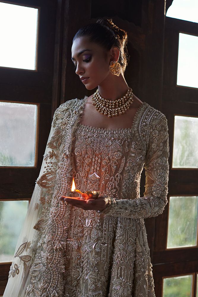 a woman in a white dress holding a lit candle