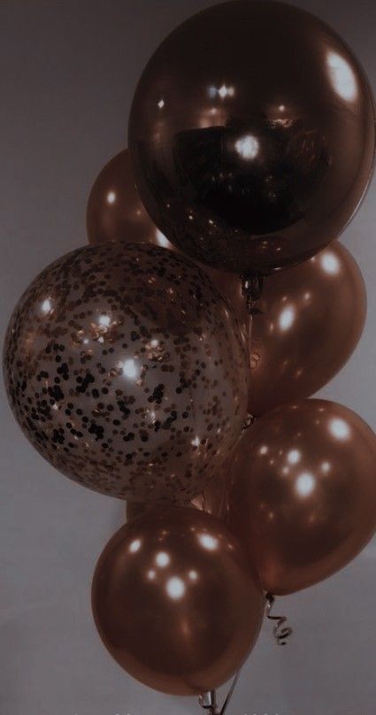 a bunch of balloons that are brown and black with speckles on them in the air