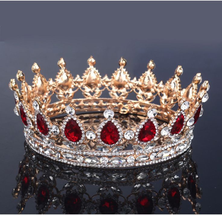 a tiara with red and white stones on it's sides, sitting on a black surface