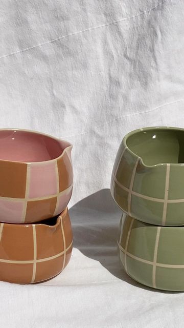 three ceramic bowls sitting next to each other on a white surface, one is green and the other is brown