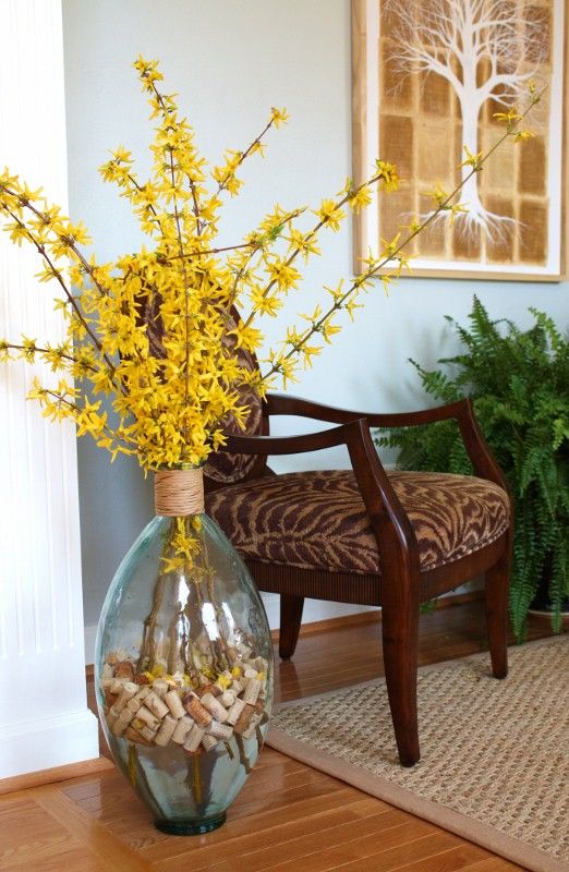 a vase filled with yellow flowers sitting on top of a wooden floor next to a chair