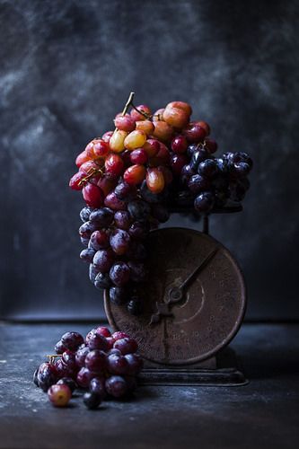 a bunch of grapes sitting on top of a table next to an old clock face