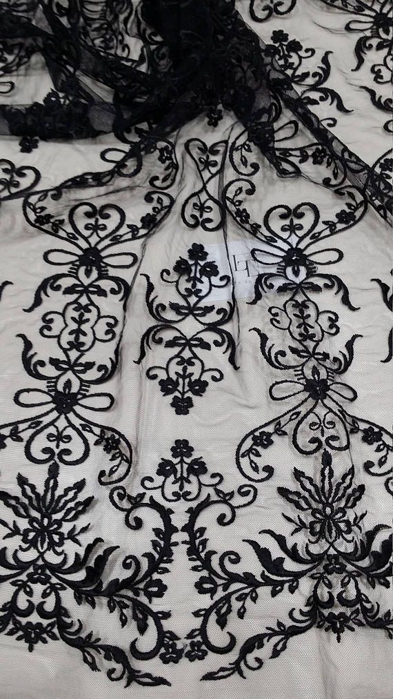 black lace on white fabric with flowers and leaves in the center, as well as an intricate design