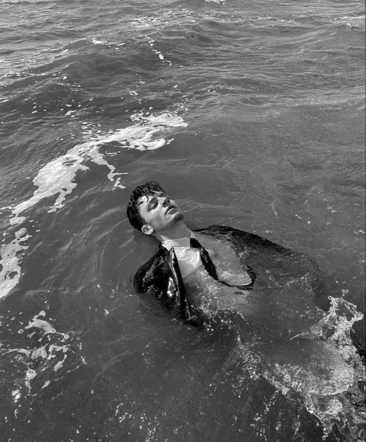 black and white photograph of a man swimming in the ocean with his head above water