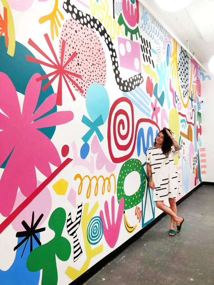 a woman standing in front of a colorful wall