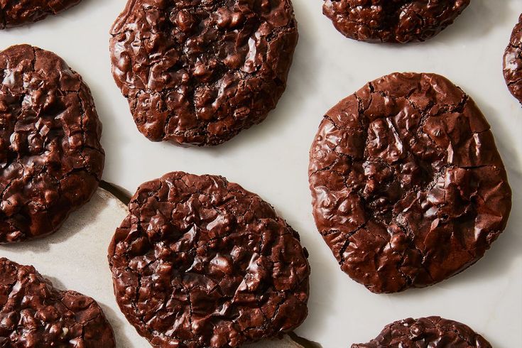 chocolate cookies are arranged on a white surface