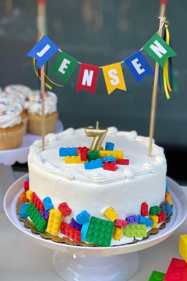 a birthday cake with legos on it and some cupcakes next to it