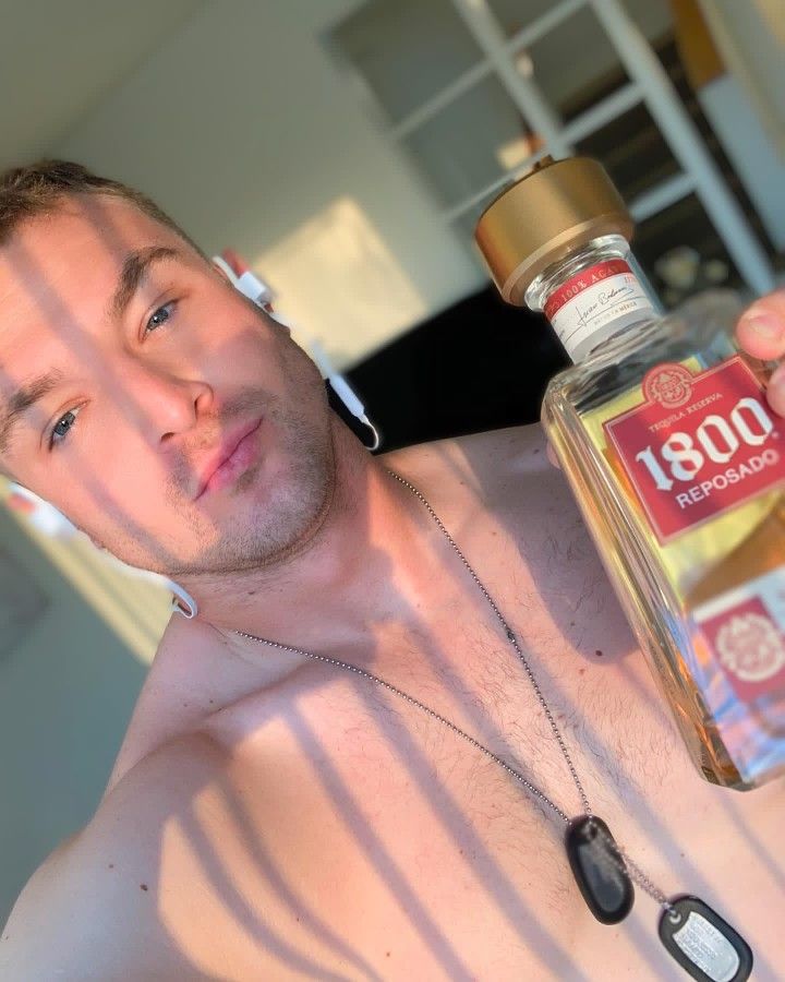 a shirtless man holding a bottle of alcohol