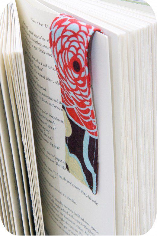 an open book with a red bird brooch on it's cover, sitting in front of a stack of books