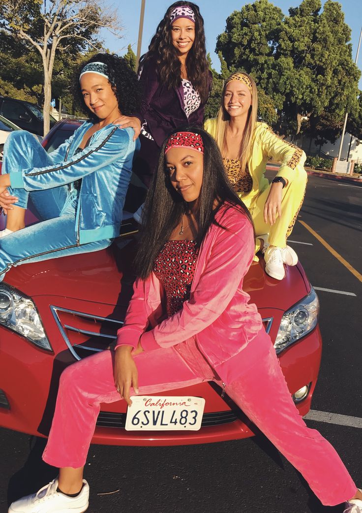 four women sitting on the hood of a car