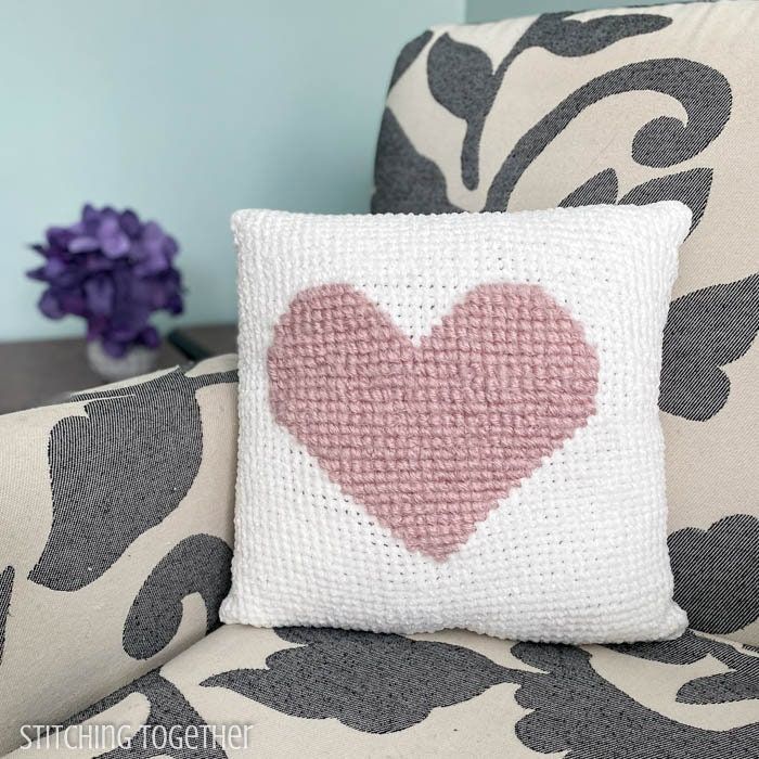 a heart pillow sitting on top of a couch