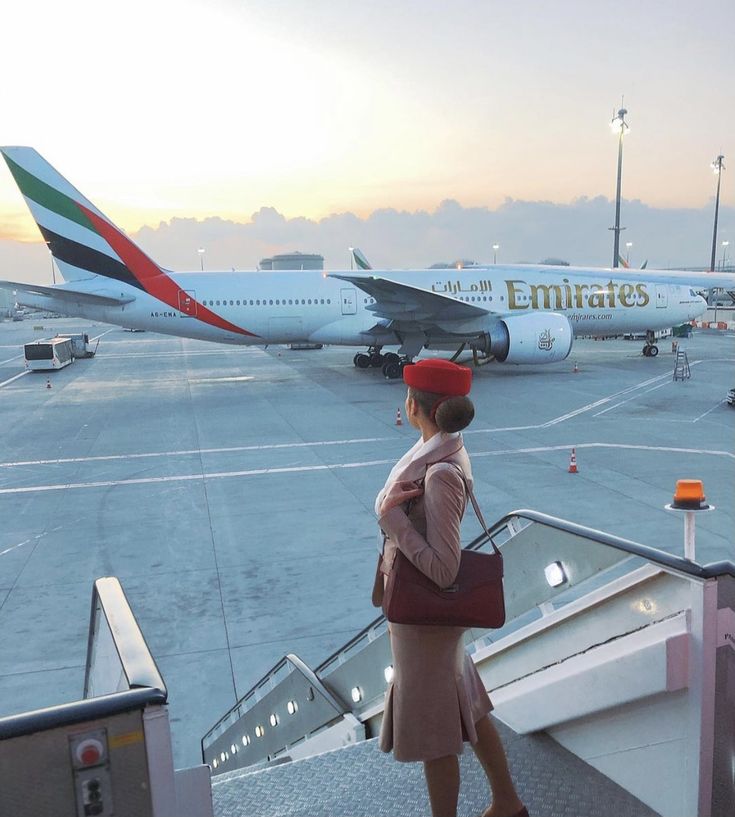 a woman walking down an escalator at an airport while another plane is on the tarmac behind her