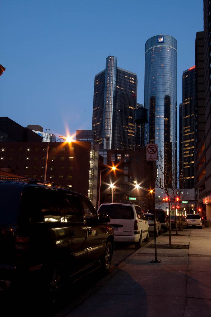 cars are parked on the side of the road in front of tall buildings at night