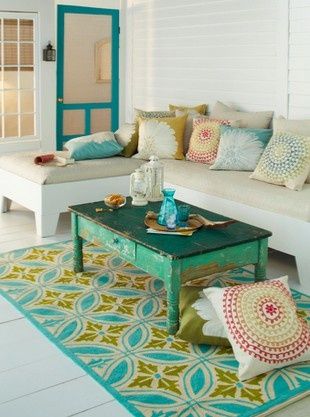 a living room filled with lots of furniture and pillows on top of a blue rug