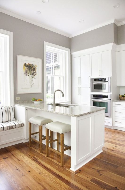 a kitchen with white cabinets and wooden floors