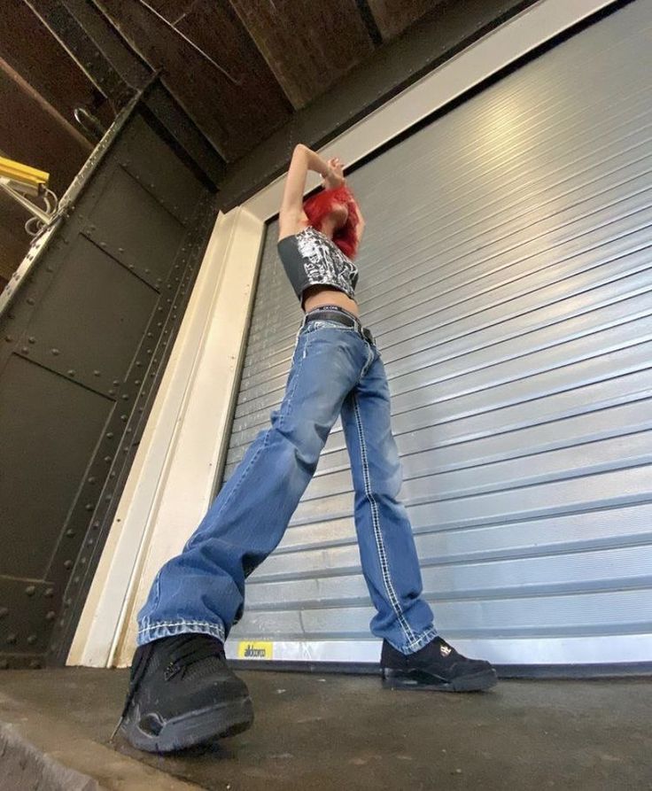 a man leaning against a garage door with his hands behind his head and arms in the air