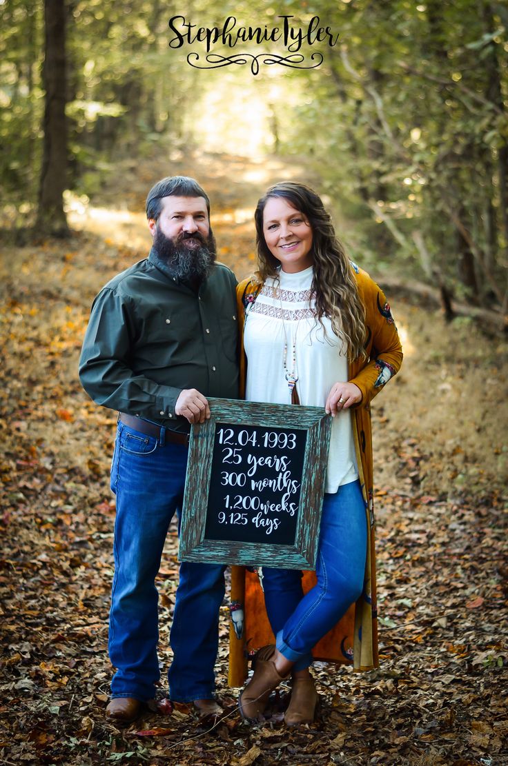 a man and woman holding a sign in the woods