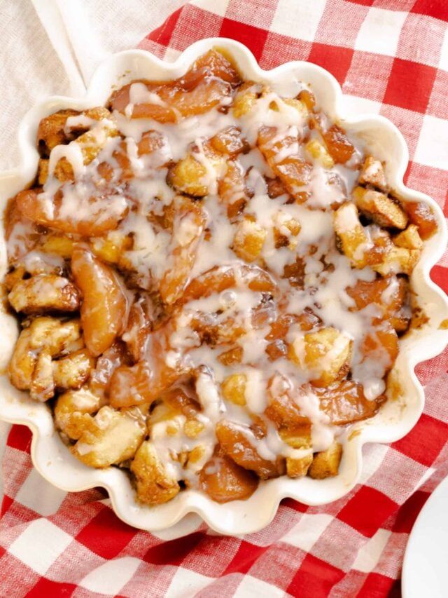 an apple cinnamon roll bake in a pie pan on a red and white checkered tablecloth