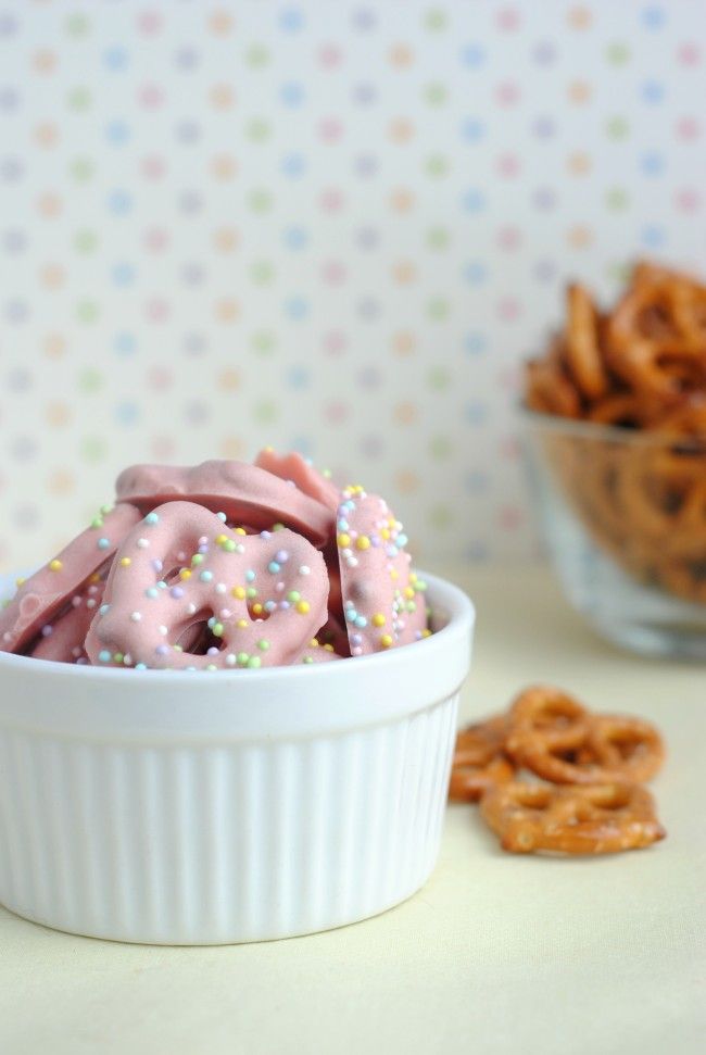 a bowl filled with pink frosted pretzels and sprinkles