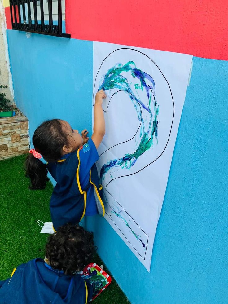 two young children drawing on a wall