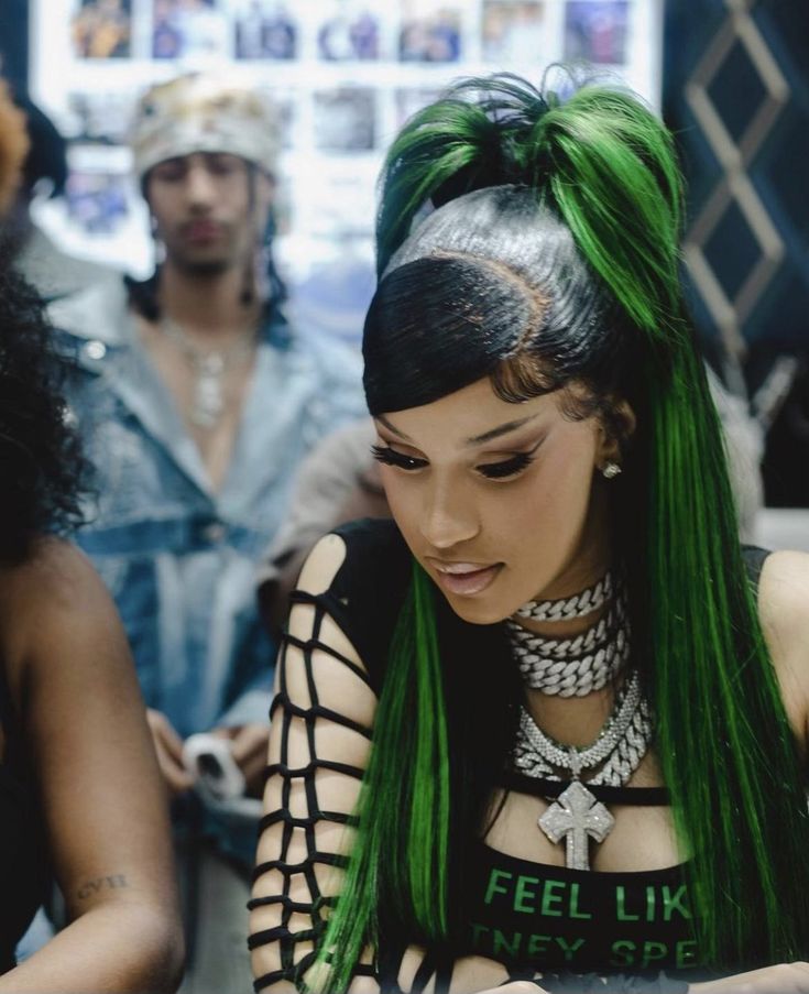 a woman with green hair is looking at her cell phone while two other people look on