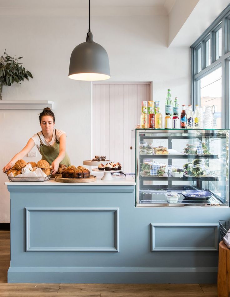 a woman standing behind a counter in a bakery