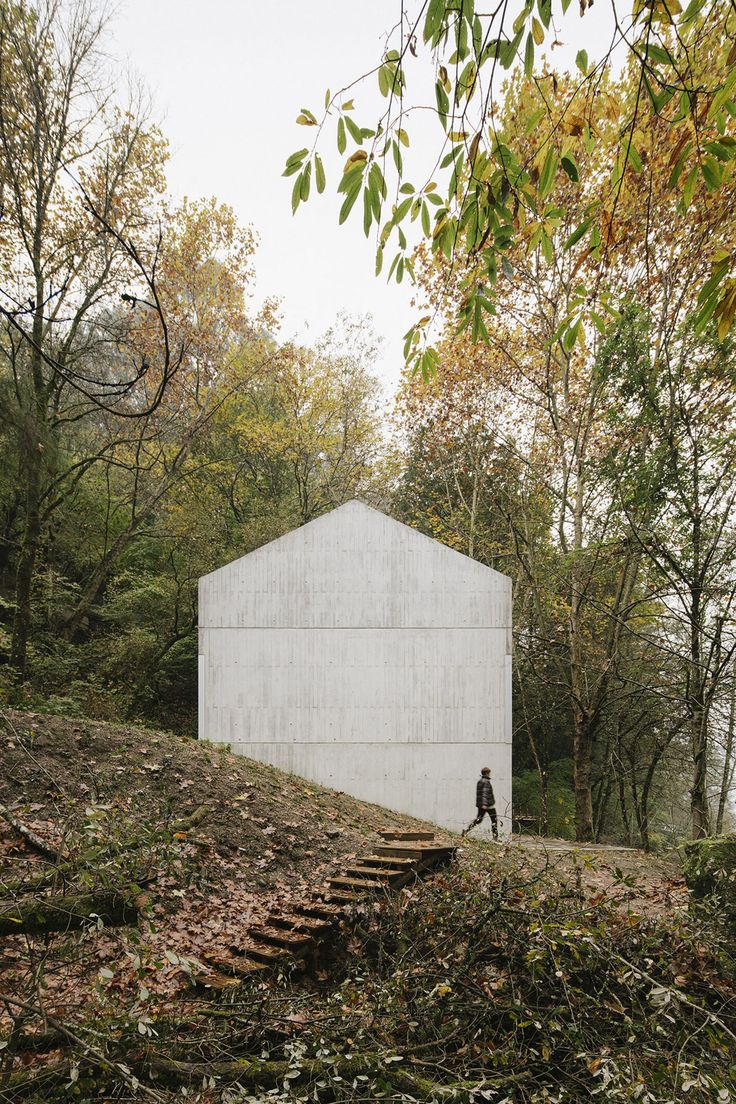 an instagramted photo of a person standing in front of a white building surrounded by trees