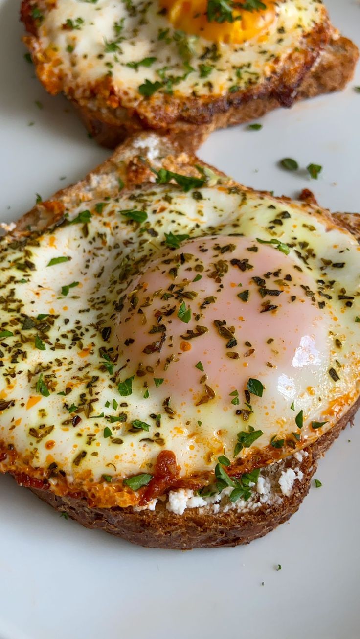 two pieces of bread with an egg in the middle on a white plate next to another piece of bread