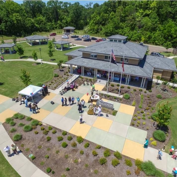 an aerial view of people walking around in front of a building with flags and trees