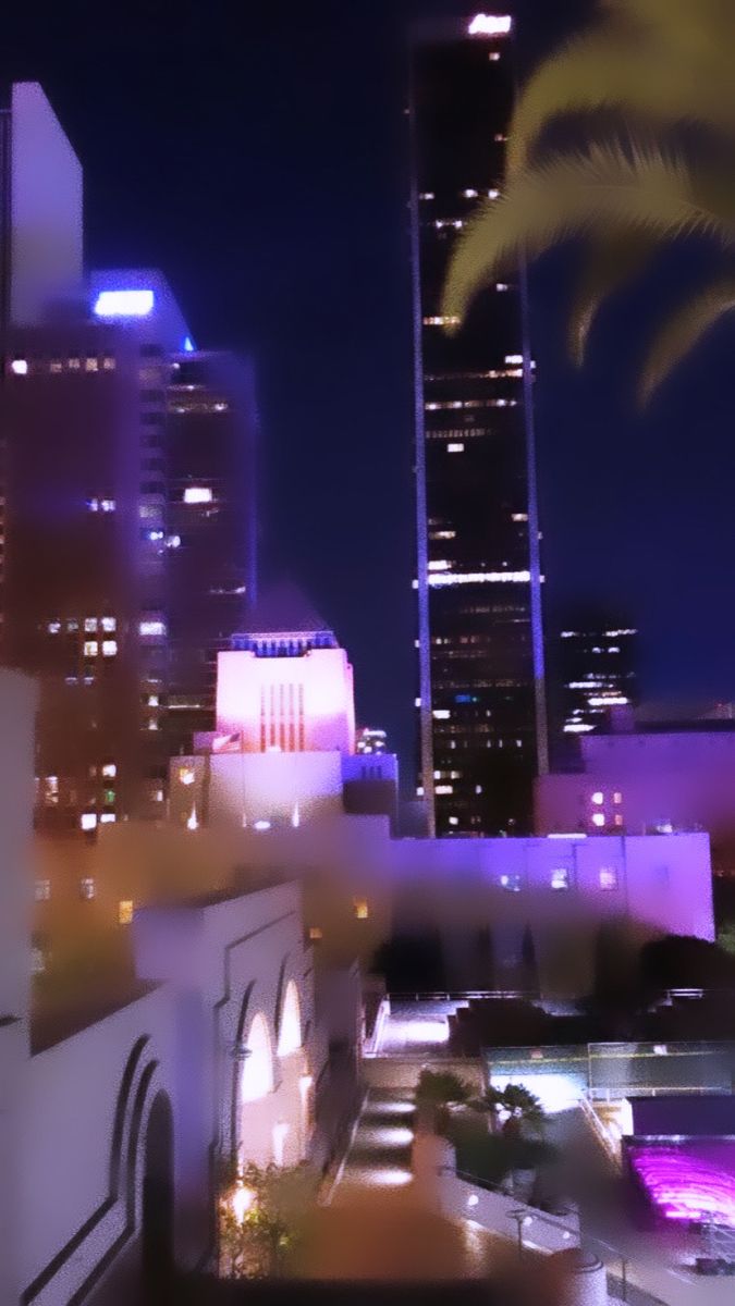 the city skyline is lit up at night with palm trees and buildings in the background