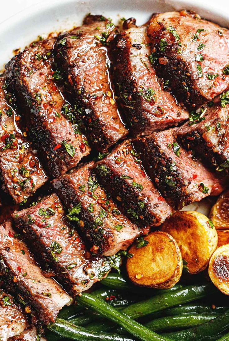 steak, green beans and potatoes on a white plate with parsley garnish