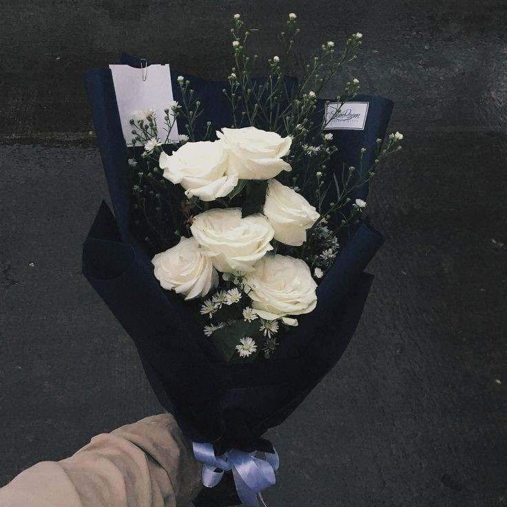 a bouquet of white roses is held by someone