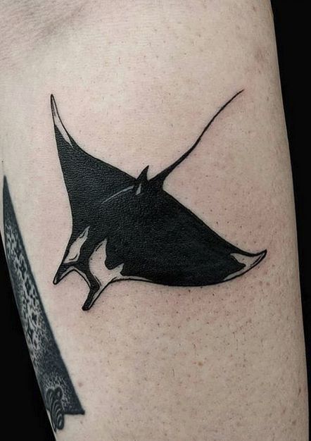 a manta ray tattoo on the right arm and shoulder, with a knife in front of it