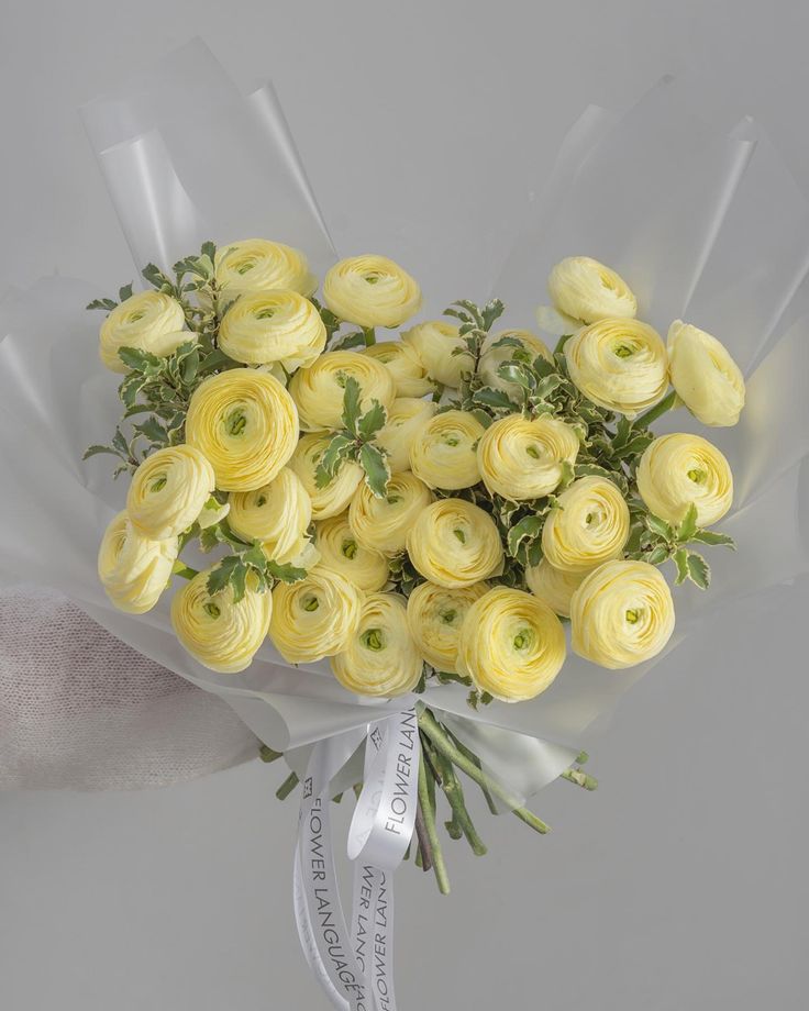 a bouquet of yellow roses wrapped in white paper