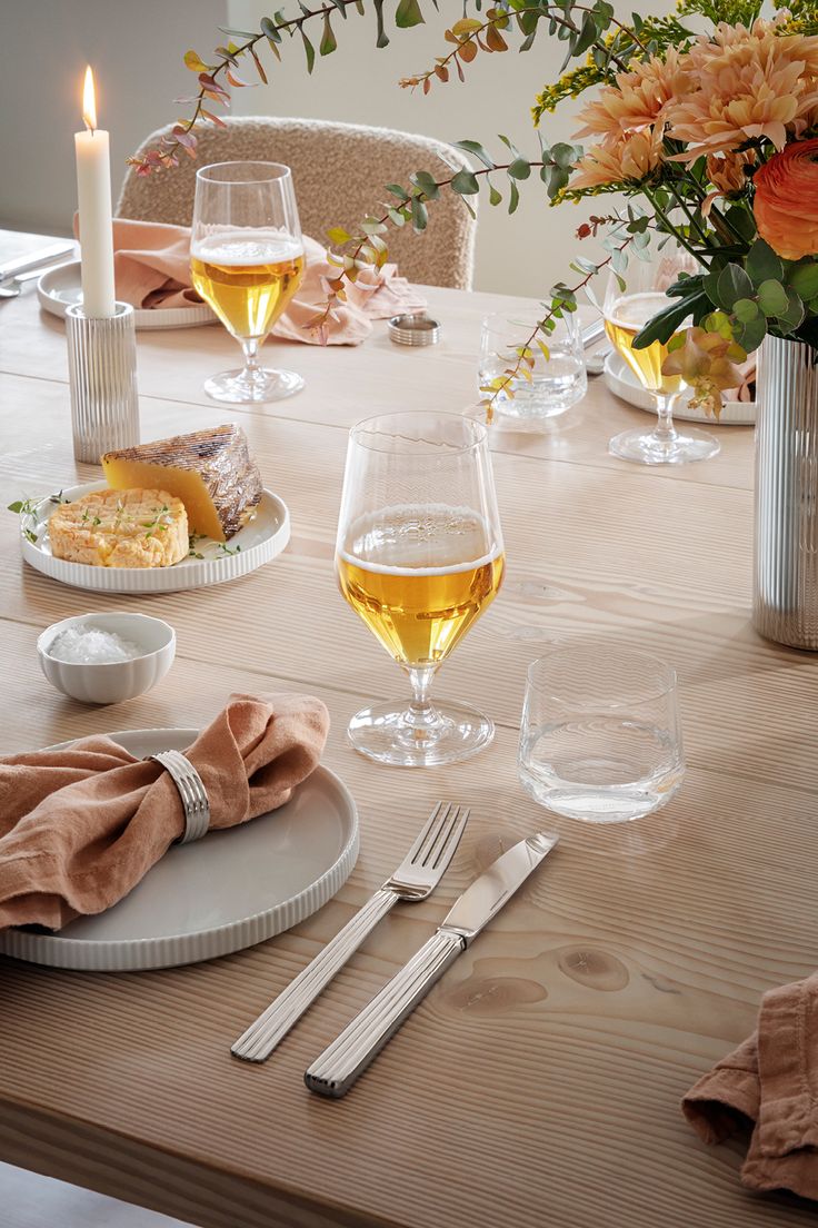 the table is set with plates, silverware and wine glasses for two people to enjoy