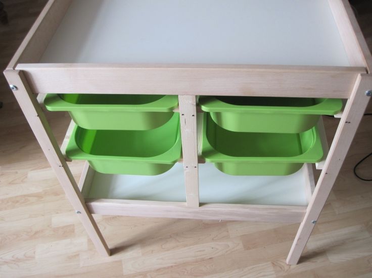 two green plastic bins sitting on top of a wooden shelf