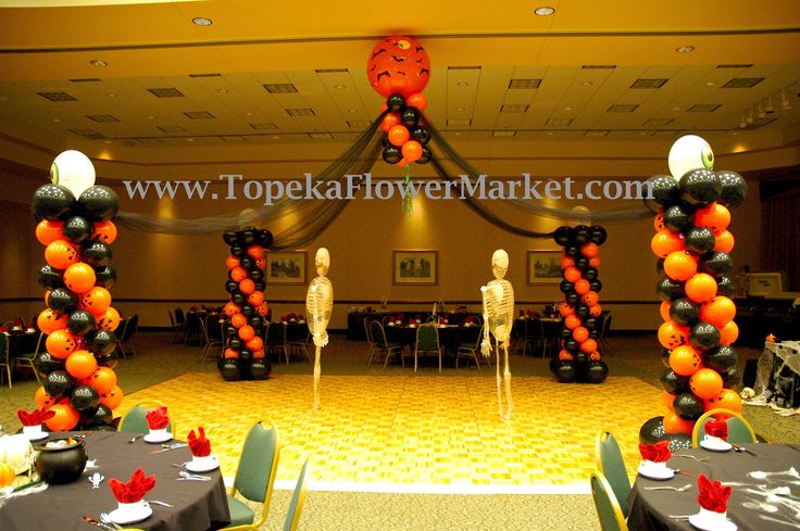 an orange and black balloon arch in the middle of a banquet hall