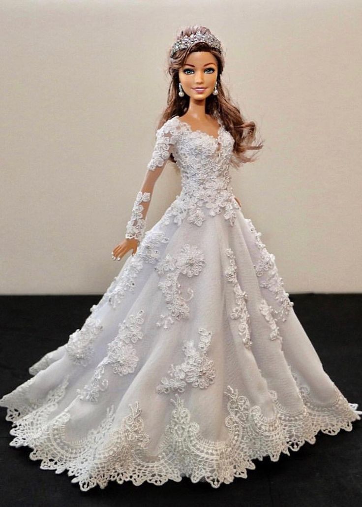 a barbie doll dressed in a white wedding dress with flowers on the skirt and tiara